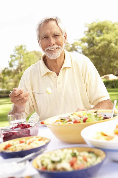 庭園でお食事を楽しんでいるシニア男性 — ストック写真