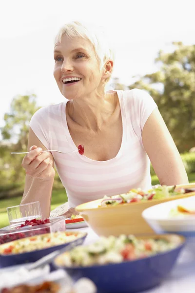 庭園でお食事を楽しんでいるシニアの女性 — ストック写真