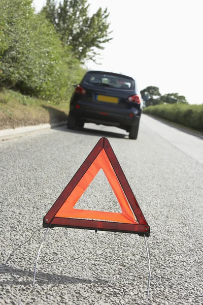 Bil uppdelade på landsväg med fara varningstecken i förgrunden — Stockfoto