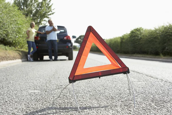Pareja rota abajo en la carretera del país con señal de advertencia de peligro en F —  Fotos de Stock