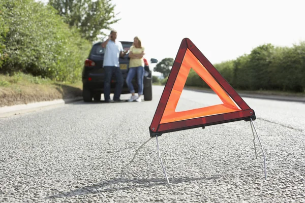 Paar uitgesplitst op landweg met gevaar waarschuwingsbord in f — Stockfoto