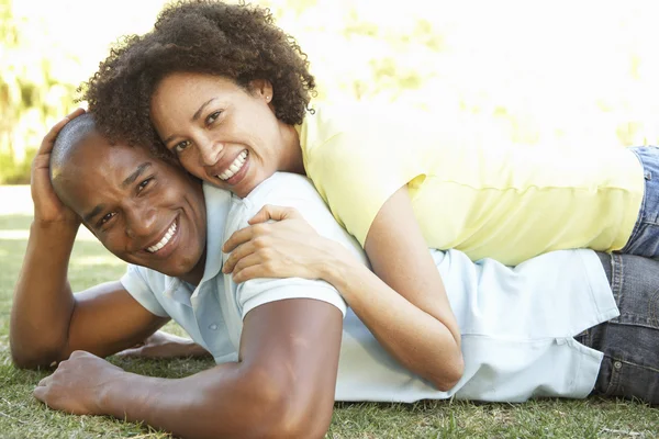 Porträt eines jungen Paares, das im Park auf Gras liegt — Stockfoto