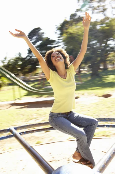 Mujer joven montando en la rotonda en el parque — Foto de Stock