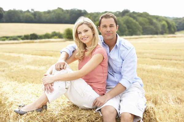 Couple Sitting On Straw Bales In Harvested Field — Stock Photo, Image