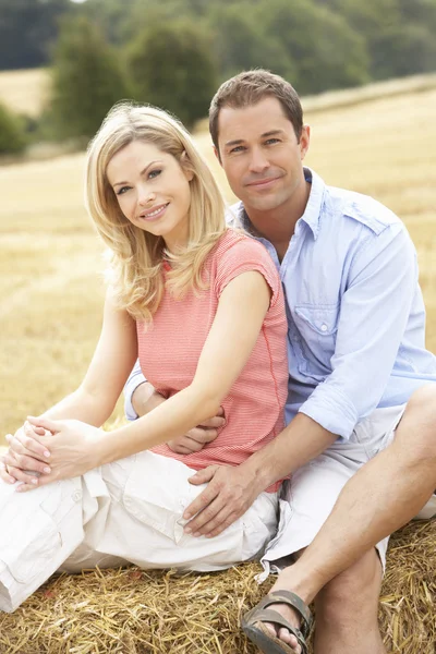 Ehepaar sitzt auf Strohballen auf abgeerntetem Feld — Stockfoto