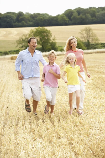 Familia corriendo juntos a través del campo cosechado en verano —  Fotos de Stock