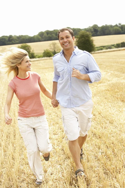 Casal correndo juntos através do campo colhido verão — Fotografia de Stock