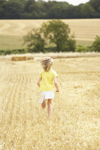 Flicka kör igenom sommaren skördade fält — Stockfoto