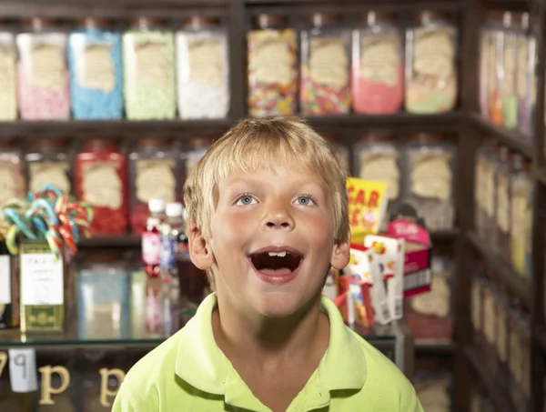 Glada pojke står i godisbutik — Stockfoto