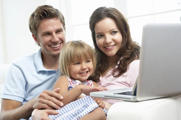 Rodzina siedzi na kanapie w domu za pomocą laptopa — Zdjęcie stockowe