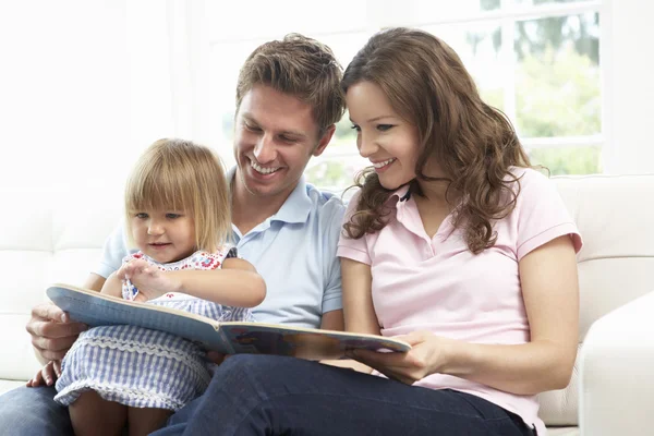 Familie sitzt zu Hause auf Sofa und liest Buch — Stockfoto
