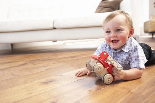 Niño jugando con coche de juguete de madera en casa — Foto de Stock