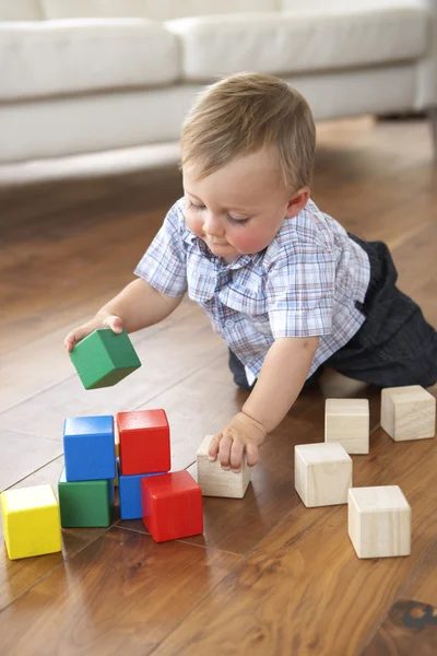 Jeune garçon jouant avec des blocs colorés à la maison — Photo