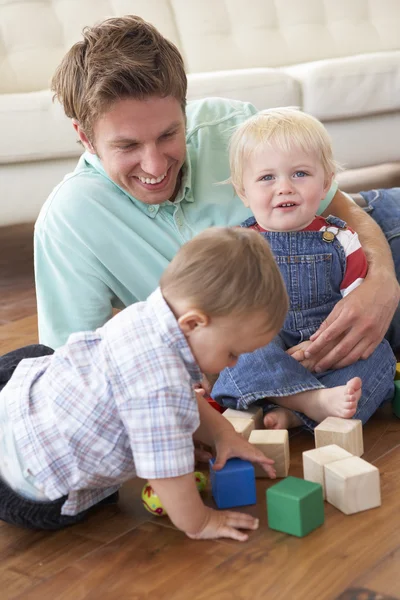 Отец и сыновья играют с цветными блоками дома — стоковое фото