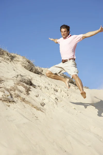 砂丘ダウンを実行しているビーチでの休暇を楽しんでいる若い男 — ストック写真