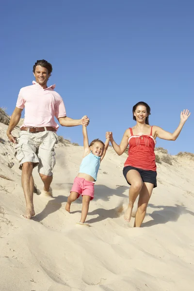 Família desfrutando de férias na praia correndo para baixo duna — Fotografia de Stock