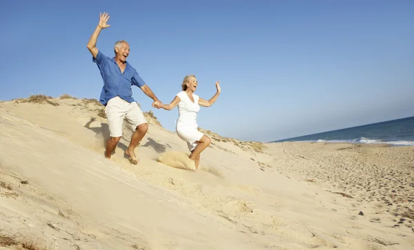高级夫妇享受海滩度假沙丘下运行 — 图库照片
