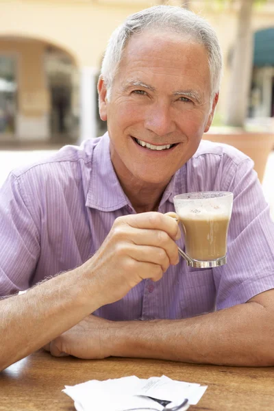 Idősebb ember élvezi a kávét és süteményeket a caf — Stock Fotó