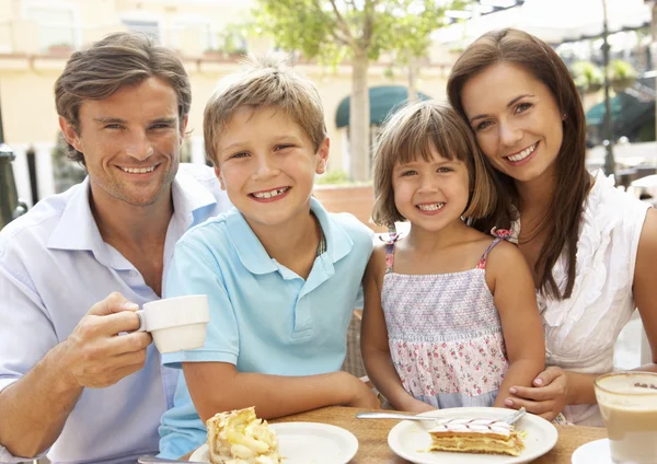 Молодая семья наслаждается чашкой кофе и тортом в кафе — стоковое фото