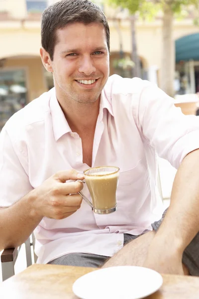 Mladý muž se těší šálek kávy v kavárně — Stock fotografie