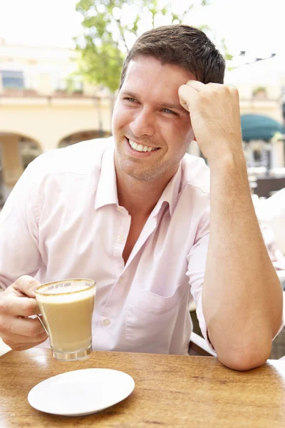 Mladý muž se těší šálek kávy v kavárně — Stock fotografie