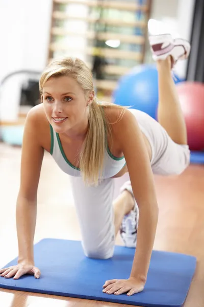 Молодая женщина делает упражнения на растяжку в тренажерном зале — стоковое фото