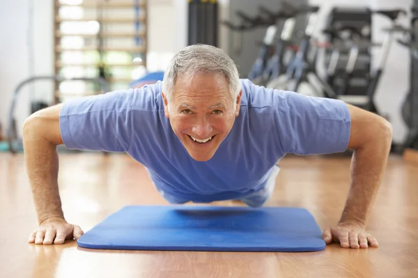 Starszy człowiek robi naciśnij przycisk up w siłowni — Zdjęcie stockowe