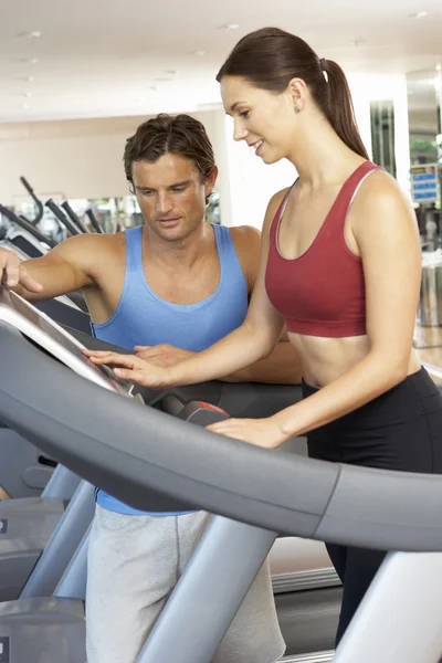Kvinna som arbetar med personlig tränare på kör maskin i gymmet — Stockfoto