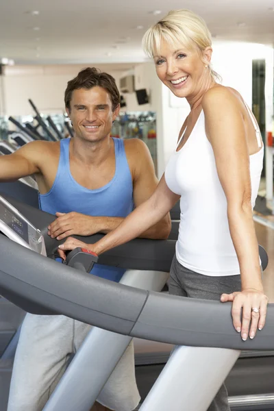 Senior Woman Working With Personal Trainer On Running Machine In — Stock Photo, Image