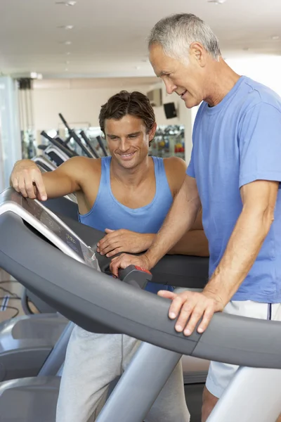 Hombre trabajando con entrenador personal en la máquina de correr en el gimnasio — Foto de Stock