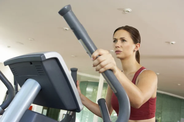 Vrouw op grensoverschrijdende trainer machine in gym — Stockfoto