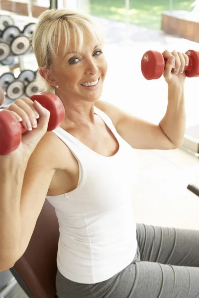 Senior vrouw die werkt met gewichten in gym — Stockfoto