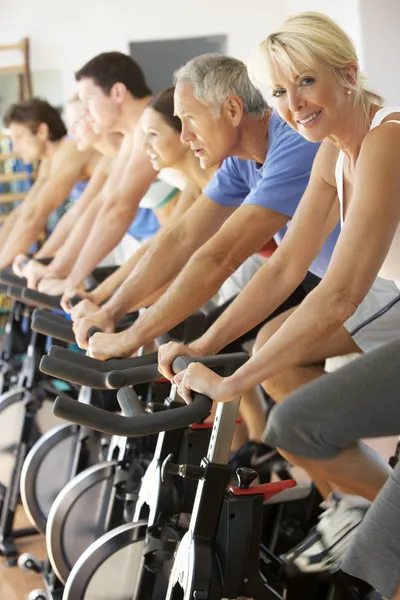 Äldre kvinna cykling i spinning klass i gym — Stockfoto