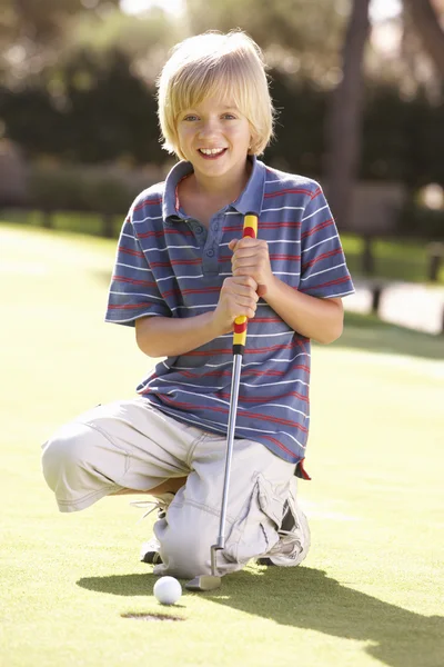 Jovem menino praticando golfe em colocar em verde — Fotografia de Stock