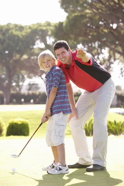Padre enseñando hijo a jugar golf en poner en verde — Foto de Stock