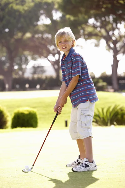 Мальчик поет гольф на зеленом — стоковое фото