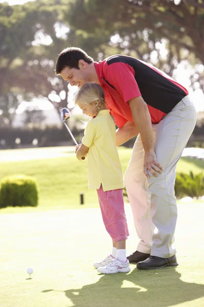 父亲教女儿打高尔夫上放绿 — 图库照片