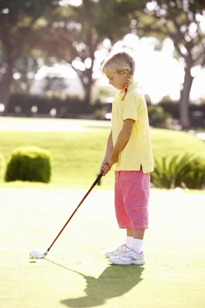 Молодая девушка играет в гольф на зеленом — стоковое фото
