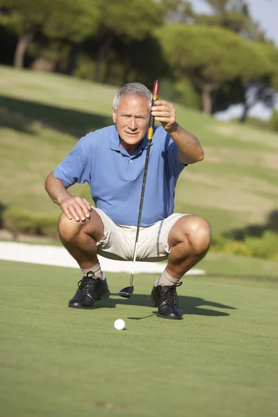 Senior mannelijke golfer op de golfbaan voering putt op groen — Stockfoto