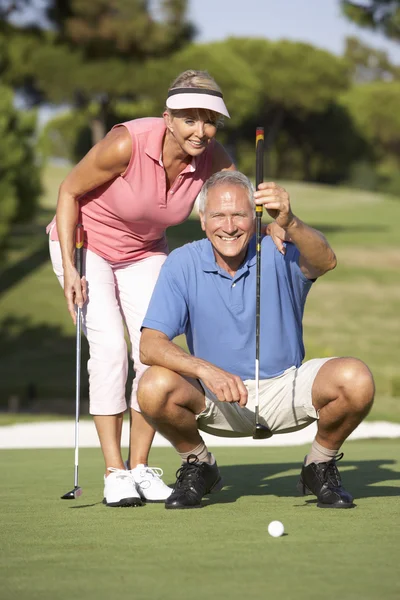 グリーンでのパットをライニングのゴルフコースでゴルフ年配のカップル — ストック写真
