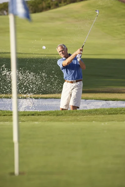 Senior männlicher Golfer spielt Bunkerschuss auf Golfplatz — Stockfoto
