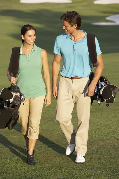 袋を運ぶゴルフ コースに沿って歩くカップル — ストック写真