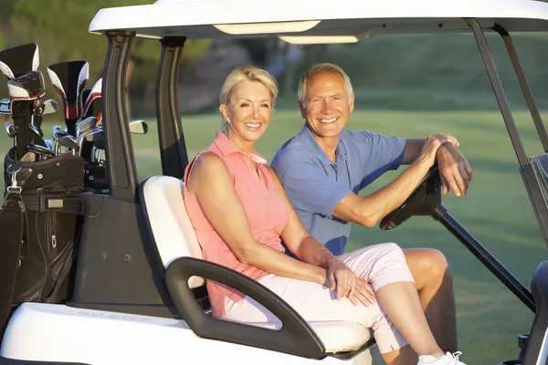 ゴルフコースでゴルフ バギーに乗る年配のカップル — ストック写真