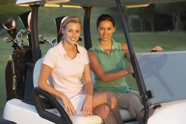 Dos golfistas femeninos que montan en golf Buggy en campo de golf —  Fotos de Stock
