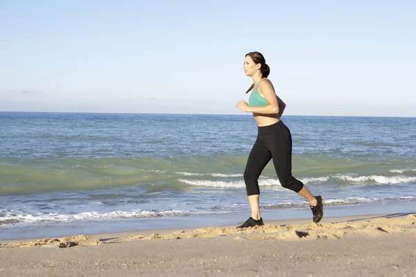 Молода жінка у фітнес одязі біжить уздовж пляжу — стокове фото