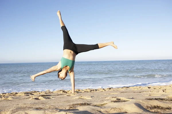 Jonge vrouw in fitness kleding draaien waterrad op strand — Stockfoto