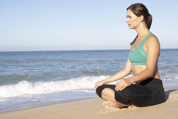 Giovane donna in fitness abbigliamento meditazione sulla spiaggia — Foto Stock