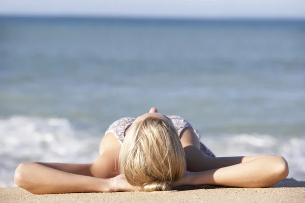 Jovem mulher tomando sol na praia — Fotografia de Stock
