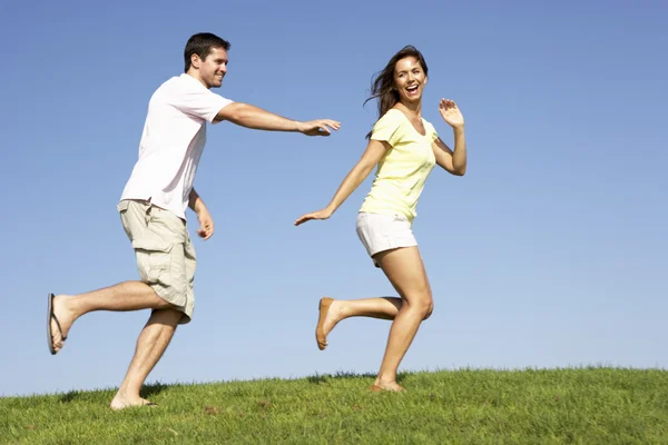 Unga par som springer genom fält — Stockfoto