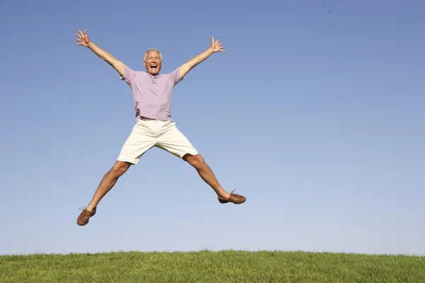 Senior man springen in de lucht — Stockfoto